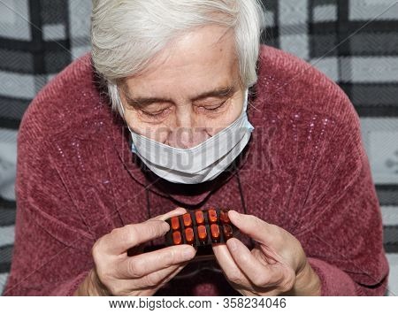 Elderly Woman In A Medical Mask. The Tablets