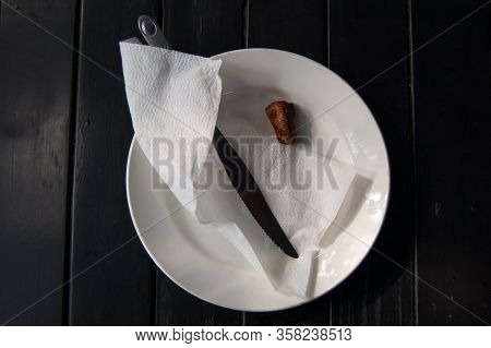 Piece Of Fried Meat Next To A Knife And Napkin On A White Plate.