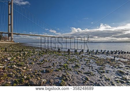 Large Suspension Bridge Spanning A Wide River Estuary On A Clear Day With Blue Sky And Clouds