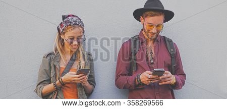 Teenegers Standing By The Wall And Using Their Smartphones- Boy And Girl Playing Games Online- Tecno