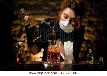 Woman Bartender In Black Clothes Pours Alcoholic Drink Into Large Glass With Ice.