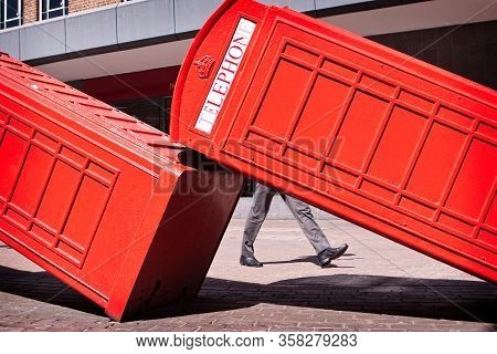 The Shoes Of A Business Man Walking Between Two Telephone Cabins