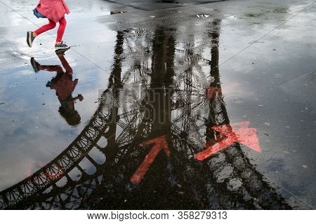 A Little Girl Running Under The Eiffel Tower When The Weather Is Raining