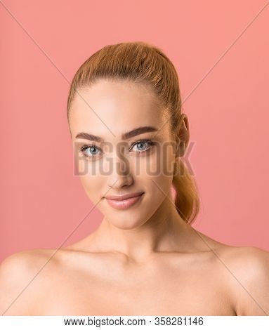 Female Beauty Portrait. Beautiful Blonde Girl Smiling Looking At Camera Posing Over Pink Backgroound