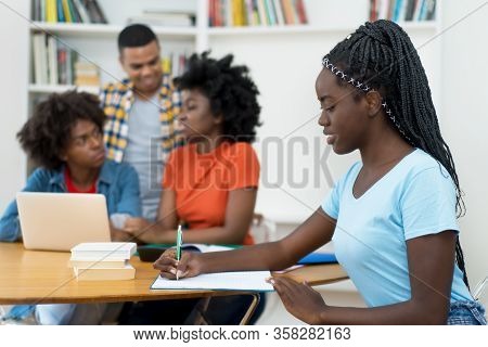 African American Young Adult With Dreads And Group Of Students At Classroom Of University