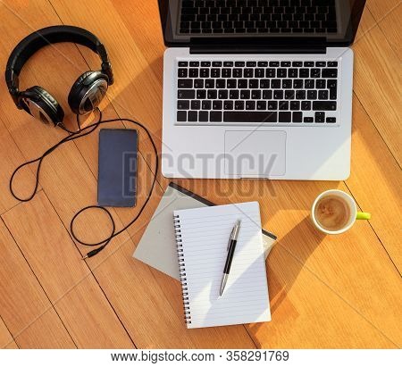 Home Office, Remote Work. Computer Laptop, Mobile Phone, Headphones And Coffee On The Floor. Telecom