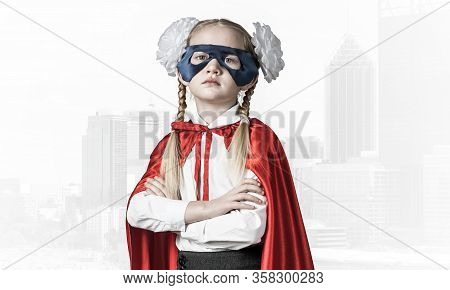 Little Confident Child In Mask And Cape Plays Cool Superhero