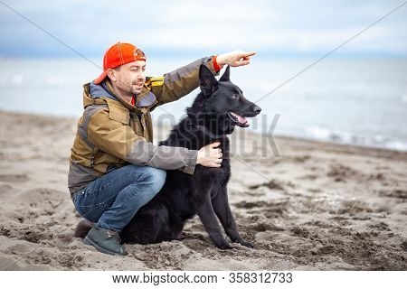 German Black Shepherd With Its Owner On The Sandy Beatch Of Black Sea