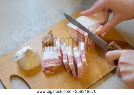 Horizontal Indoor Picture Of Unknown Person Holding Knife, Cutting Lard Into Slices, Preparing For L