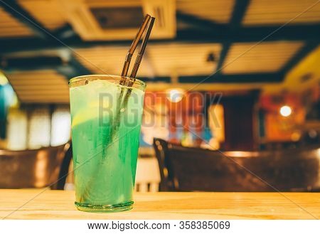Green Tasty Alcohol Or Non-alcohol Cocktail With Ice And Piece Of Lemon Inside. Stand On Table. Bar 
