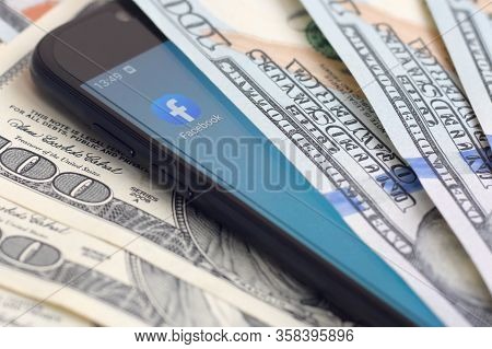 Smartphone Screen With Facebook App And Lot Of Hundred Dollar Bills. Business And Social Networking 