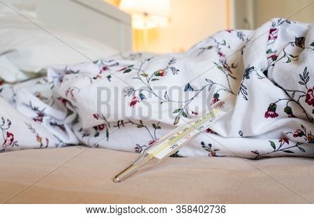  thermometer in bed showing fever coronavirus or COVID-19 