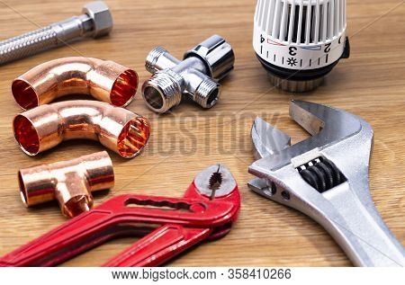 The Photo Shows Different Tools For Sanitary Installation On A Wooden Table
