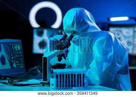 Scientist In Protection Suits And Masks Working In Research Lab Using Laboratory Equipment: Microsco