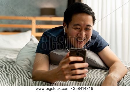 Portrait Of Happy 30s Aged Asian Man In Casual Clothing Making Facetime Video Calling With Smartphon