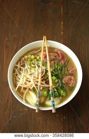 Asian noodle soup with beef, shives, onion, bean sprout and lime