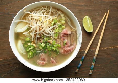 Asian noodle soup with beef, shives, onion, bean sprout and lime