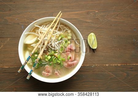 Asian noodle soup with beef, shives, onion, bean sprout and lime