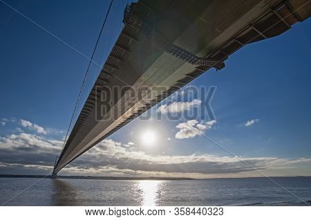 Large Suspension Bridge Spanning A Wide River Estuary On A Clear Day With Blue Sky And Clouds