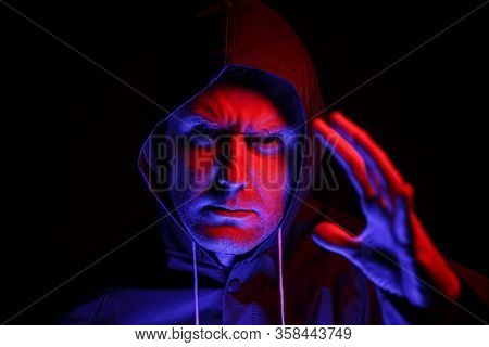A Man In A Protective Suit In A Dark Room. Halloween Image Concept. Virus Protection. Illuminated Wi