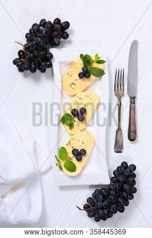 Halumi Cheese With Blueberries And Grapes On A White Plate With Vintage Appliances With Fork And Kni