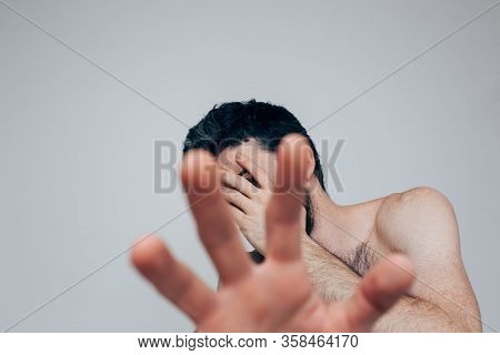 Young Man Isolated Over Background. Picture Of Guy Cover Face With Hand And Show Another Close To Ca