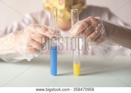 A Child In A White T-shirt In The Laboratory Is Studying Chemistry . Young Scientists In Protective 