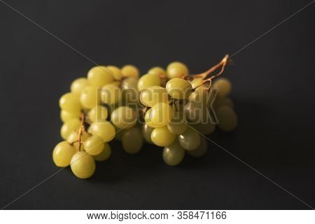 A Ripe Yellow Bunch Of Grapes Lies On A Black Background.