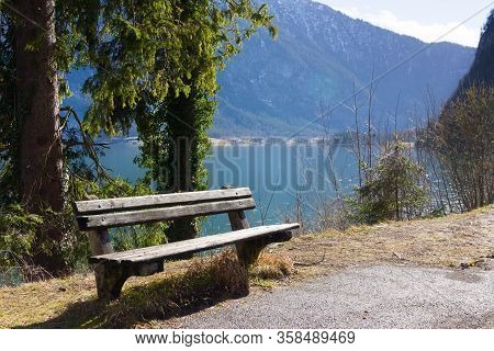 Empty Wooden Bench On Shore Of Beuatiful Lake In Austrian Alps. Winter Sunny Morning On Lake Hallsta