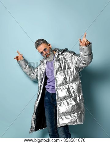 Gray-haired, Bearded Aged Male In Purple Pullover And Sunglasses, Silver Colored Down Puffy Jacket, 