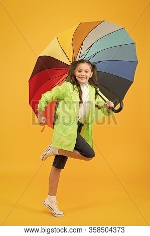 Simple Happiness. I Do Not Care. Carefree Schoolgirl Jumping With Umbrella Waterproof Rain Coat. Aut