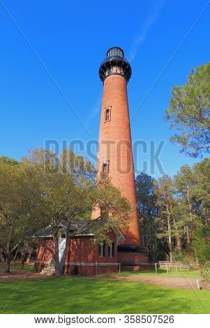 The Red Brick Structure Of The Currituck Beach Lighthouse Rises Overover A Small Entry House And Pin
