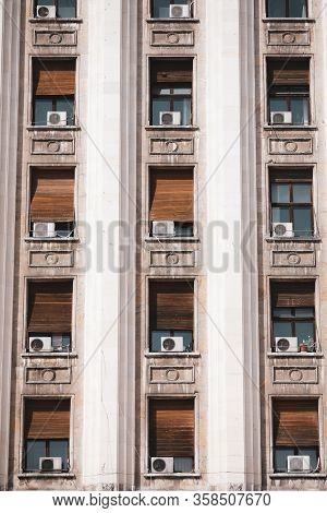The Exterior Of An Old Soviet Era Style Building With Window Air Conditioning Machines.