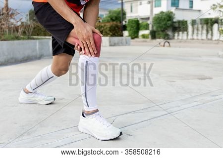 Close Up On Knee Injury. The Man Use Hands Hold On His Knee While Running In The Park