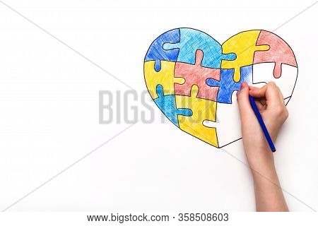 World Autism Awareness Day. Childrens Hand Draws Heart From Multi-colored Puzzles. Mental Health Car