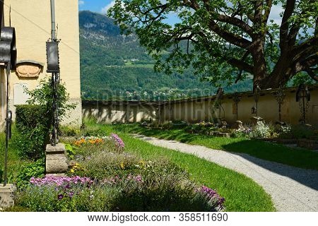 Old Graves In The Nonnberg Abbey Courtyard In Salzburg, Austria; The Nearby Gaisberg Looms Over The 