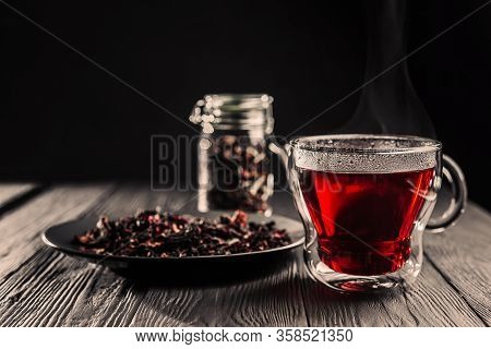 Cup Of Freshly Brewed Red Karkade Tea, Rose Tea Ceremony, Dark Moody.hot Water Is Poured From The Ke