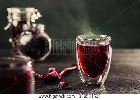 Cup Of Freshly Brewed Red Karkade Tea, Rose Tea Ceremony, Dark Moody.hot Water Is Poured From The Ke