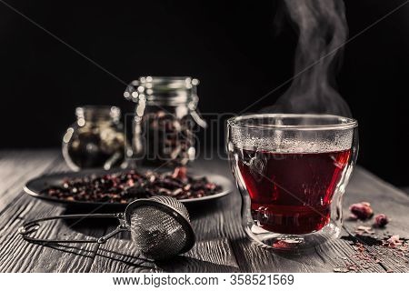 Cup Of Freshly Brewed Red Karkade Tea, Rose Tea Ceremony, Dark Moody.hot Water Is Poured From The Ke
