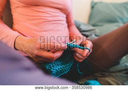 Woman Crochets Sitting In Bed, Needlework During Quarantine, The Girl Knits From Thick Blue Yarn, Fe