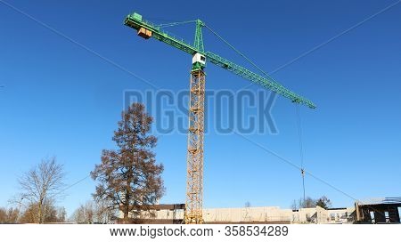 Tower Crane Is Working At A Construction Site. Blue Sky Background.