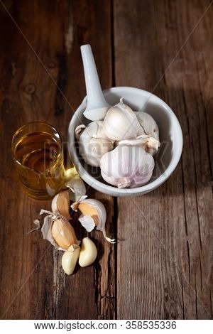 Garlic Oil And Garlic On A Wooden Table.