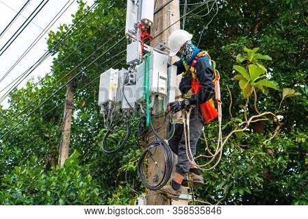 A Professional Electrician Performs Installation Work On A Pole. An Electrician In Professional Equi