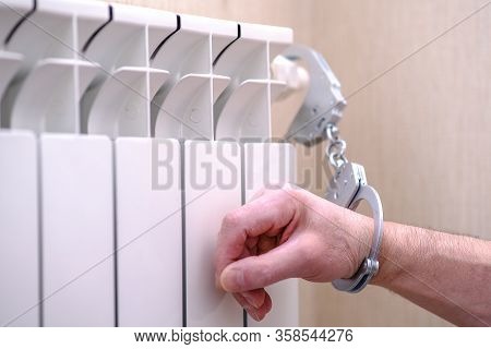 Handcuffs On The Hand. The Hand Is Handcuffed To The Radiator Of The Heater. The Concept Of Self-iso