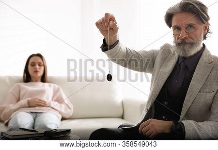 Psychotherapist Using Pendulum During Hypnotherapy   Session In Office
