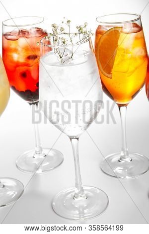 Spritz fruit cocktails. Alcohol soft drinks in glasses side view. Refreshment beverage with coconut, berry, orange in drinkware. Exotic summer beach cocktail portions with crushed ice in glassware
