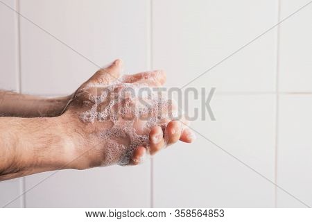 Man Cleaning His Hands Using Liquid Disinfectant Soap And Water In Bathroom.