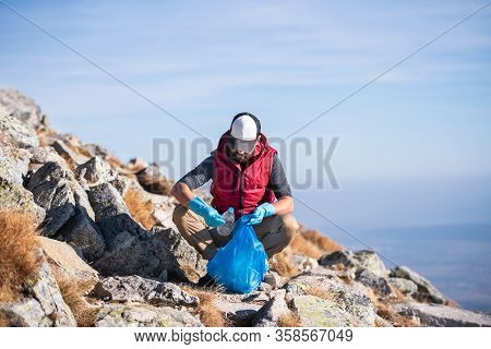 Man Hiker Picking Up Litter In Nature In Mountains, Plogging Concept.