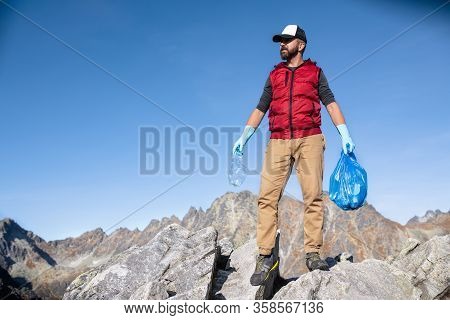 Man Hiker Picking Up Litter In Nature In Mountains, Plogging Concept.