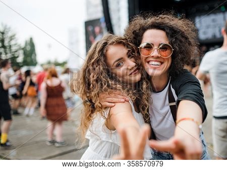 Young Girl Friends At Summer Festival, Posing For Photograph.
